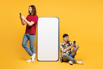 Full body young two friends buddies men wear casual clothes together sit big huge blank screen...