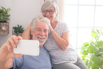 Video call concept. Bonding senior couple using smartphone for online communication via video meeting, smiling white-haired man and woman enjoying tech and social