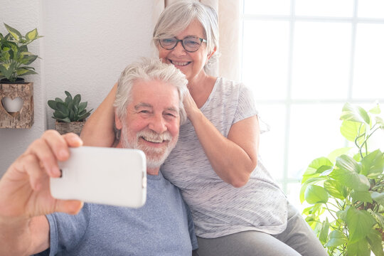 Video call concept. Bonding senior couple using smartphone for online communication via video meeting, smiling white-haired man and woman enjoying tech and social
