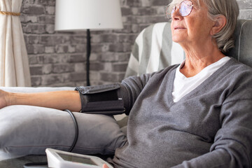 Senior woman using medical device to check measure blood pressure - elderly woman suffering from...
