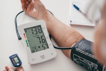 Elderly woman using medical device to measure blood pressure - senior woman suffering from...