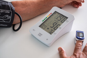 Old caucasian man using medical device to measure blood pressure - senior man suffering from...