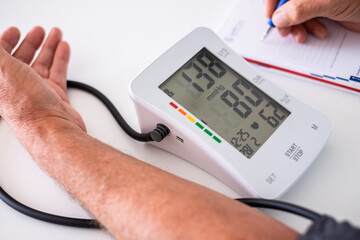 Old caucasian man using medical device to measure blood pressure - senior man suffering from...