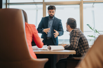 Three colleagues engaged in a discussion in a contemporary workspace. The image highlights...