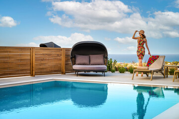 Luxury travel moment by pool with stylish woman gazing at sea. Perfect vacation scene highlighting...