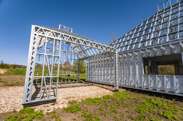 New home under construction using steel frames against cloudy sky. Metal frame of a new modern...