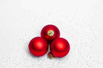 Three red Christmas baubles lying in the snow, magic world concept