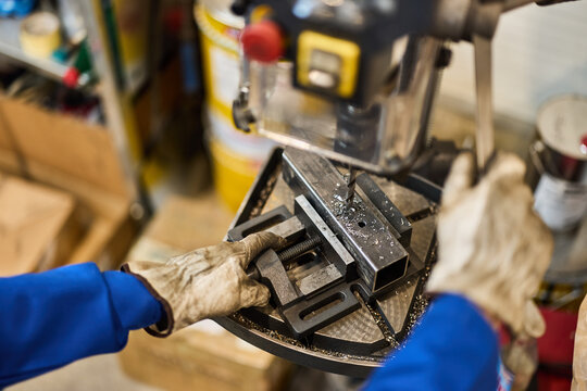 Worker Operating Drill Press on Metal Piece in Industrial Workshop - Powered by Adobe