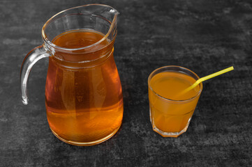 A glass jug filled with cold brew tea sits next to a glass on a kitchen counter