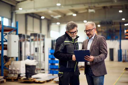 Two Professionals Reviewing a Document Together Inside a Modern Industrial Facility