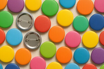 Colorful circular pins spread across a surface with two blank backs waiting for design