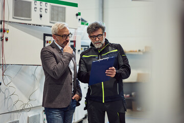 Senior Engineers Discussing Project Details While Reviewing Blueprints in a Facility