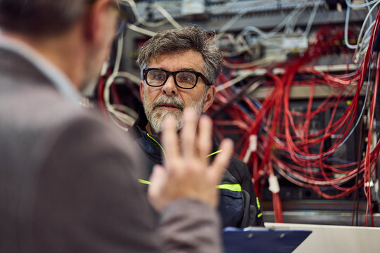 Technicians Examining a Server Room with Networking Cords and Equipment - Powered by Adobe