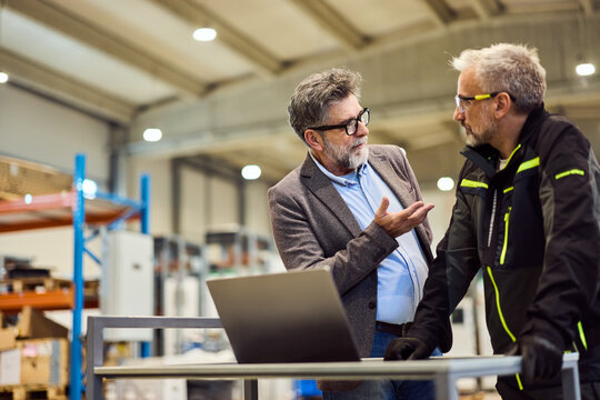 Two Professional Colleagues Discussing Work in a Modern Industrial Setting