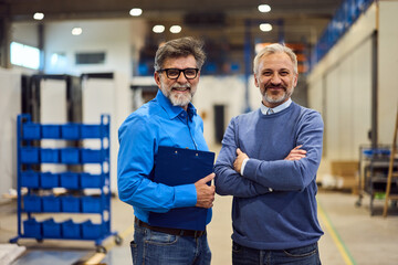 Two Senior Engineers Smiling Together in a Modern Industrial Factory Setting
