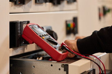 Electrician Testing Equipment with Digital Multimeter in Industrial Setting