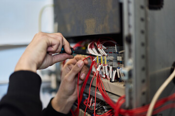 Technician Repairing Electrical Panel with Numerous Wires and Tools Up Close