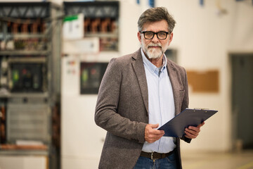 Senior Professional Holding Clipboard in Industrial Workplace