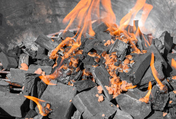 Orange flames of fire rising from the burning charcoal