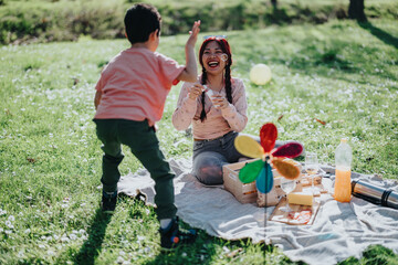 Filipino family spending quality time outdoors in a park. The mother and child share laughs as they...