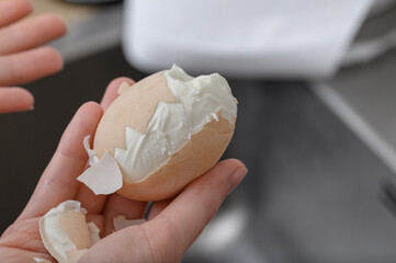 Peeling a boiled egg from its shell, the shell does not come off the egg well, close-up