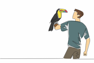 Fototapeta premium Single one line drawing keel billed toucan perched on hand of man. This species is found in tropical forests. Eat insects or fruit. Pets. Man Holding Bird. Continuous line design graphic illustration