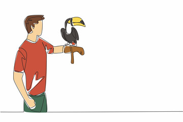 Fototapeta premium Single one line drawing toucan bird perched on hand of man. The most attractive bird in the zoo. Long orange beak. Not good at flying. Man Holding Bird. Continuous line design graphic illustration