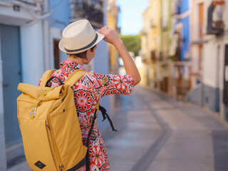 Woman in dress strolls through colorful streets of Spanish coastal town of La Vila Joiosa or Villajoyosa. sunny winter atmosphere highlights charm of Mediterranean architecture and quiet seaside life