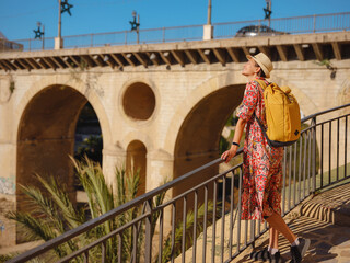 Woman in dress strolls through colorful streets of Spanish coastal town of La Vila Joiosa or Villajoyosa. sunny winter atmosphere highlights charm of Mediterranean architecture and quiet seaside life