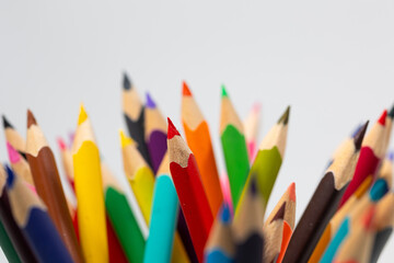 A vibrant collection of colored pencils stands upright against a neutral background, symbolizing...