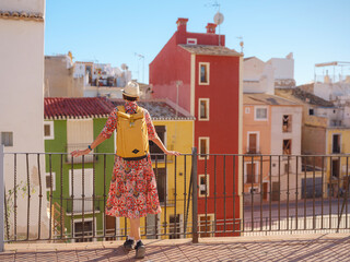 Woman in dress strolls through colorful streets of Spanish coastal town of La Vila Joiosa or Villajoyosa. sunny winter atmosphere highlights charm of Mediterranean architecture and quiet seaside life