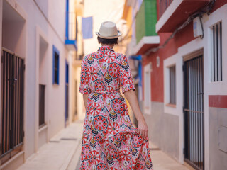 Woman in dress strolls through colorful streets of Spanish coastal town of La Vila Joiosa or Villajoyosa. sunny winter atmosphere highlights charm of Mediterranean architecture and quiet seaside life