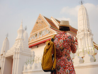 Woman Exploring Colorful Streets Near Buddhist Temples in Bangkok. Female traveler strolling through charming streets of Bangkok, surrounded by traditional architecture and beautiful Buddhist temples.