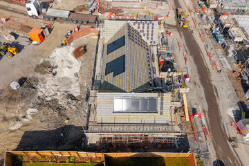 Aerial view from drone at construction workers installing solar panels on rroof of new house in...