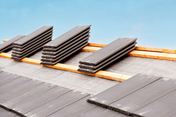Roof tiles stacked and ready for installation on a residential building during overcast weather...