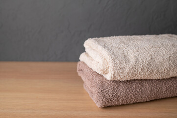 Stack of neutral colored cotton bath towels on wooden table. Concept of cleanliness, cleaning,...
