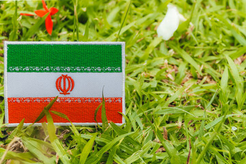 Eco-friendly Iranian embroidered flag on natural grass, bright fabric on the left with copy space...
