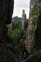 a young male tourist is looking at the rocky peaks in the mountains