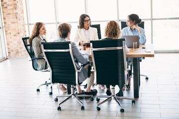 Professional team members collaborating during a business meeting in a modern office space,...