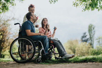 Three people, including two in wheelchairs, are seen with smiling faces under a lush green canopy,...