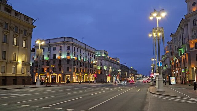 MINSK - MAR 25, 2025: A city street at night with a few cars and a few pedestrians. The street is lit up with lights from the buildings and street lamps on Independence Avenue