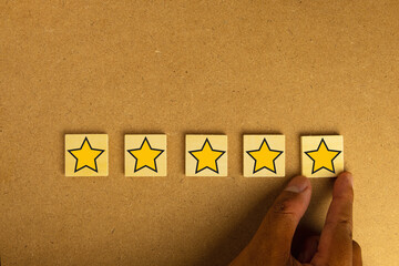 A hand placing the fifth star for a five-star rating. Concept for excellent customer satisfaction,...