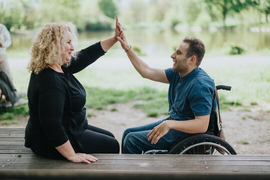 Joyful interaction between a wheelchair user and a woman outdoors, symbolizing support and friendship. Their upbeat demeanor and positive exchange reflect values of inclusion and mutual encouragement.