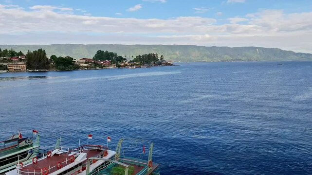 Lake Toba's natural landscape is filled with tropical trees. Activity of fishing boats, speed boats on the largest volcanic lake in Indonesia.