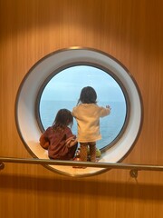 Children looking out through a round window on a ferry