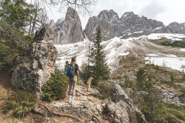 Naklejka premium Woman hiking with Czechoslovakian Wolfdog in snowy Dolomites mountain landscape, Italy.