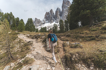 Woman hiking with Czechoslovakian Wolfdog in snowy Dolomites mountain landscape, Italy.