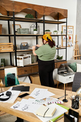 Elegant pretty woman organizing her art studio with creativity and style during a sunny afternoon