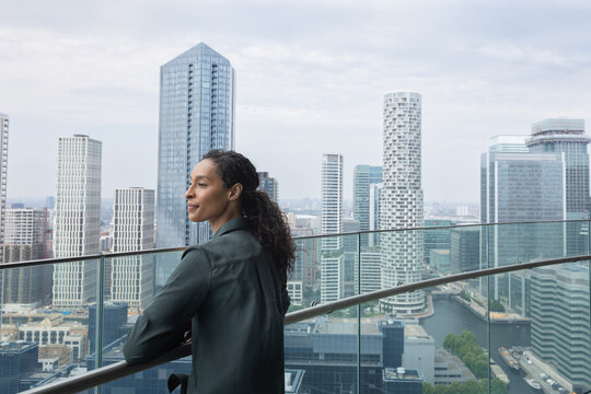 Contemplative businesswoman Overlooking Modern Cityscape