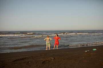 Two women enjoying a joyful seaside moment during vacation, barefoot on the beach, sharing laughter and sunshine. A memory of freedom, travel, and connection